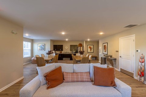 A living room with a grey couch and orange pillows.