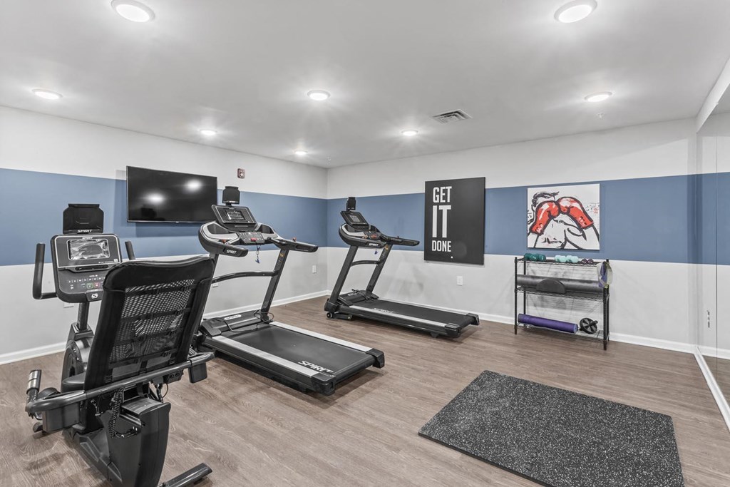 a gym with treadmills and a tv on the wall