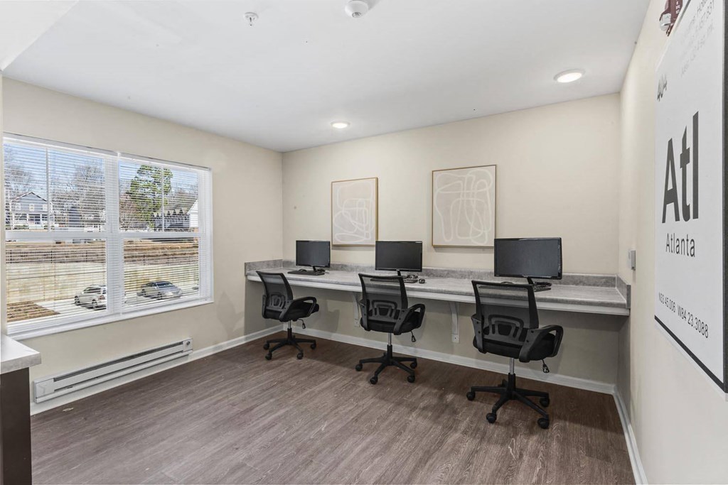 a home office with three desks and a window