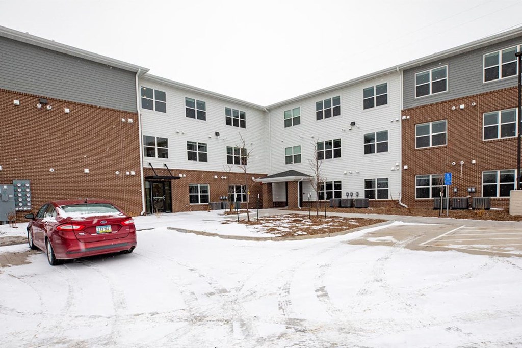 a red car parked in front of a brick building in the snow
