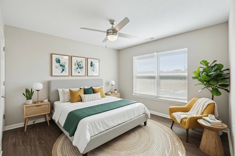 A bedroom with a bed, a chair, and a ceiling fan.