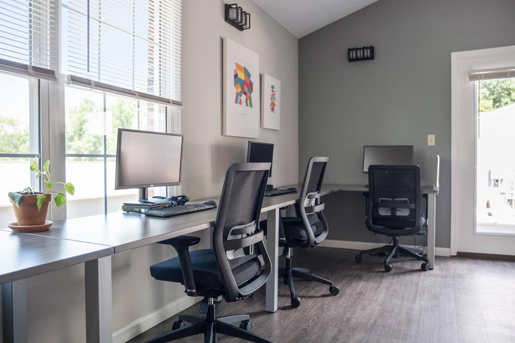 three desks with computers and chairs in an office