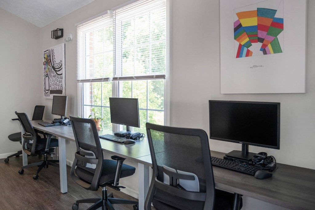 a computer room with desks and chairs and a window