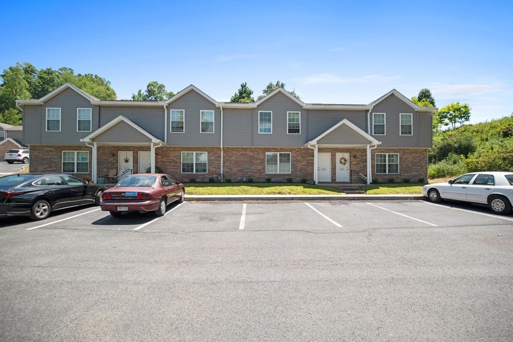 a parking lot in front of a large apartment building with cars parked