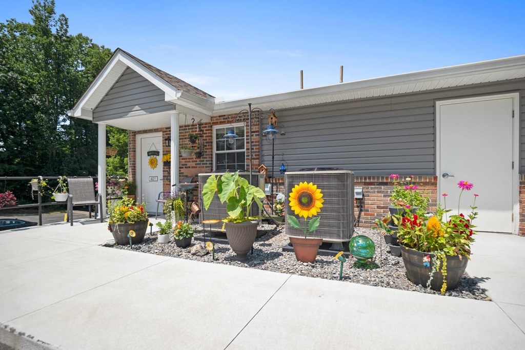 the front yard of a house with flowers and potted plants