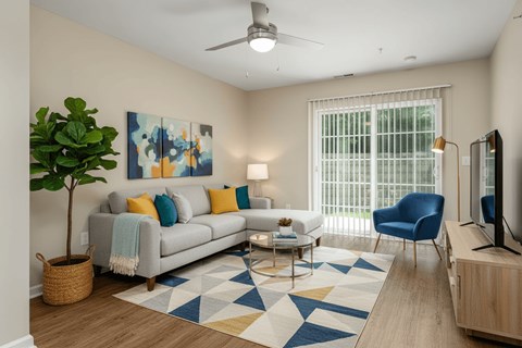 A living room with a grey couch, a blue chair, a plant, and a painting on the wall.