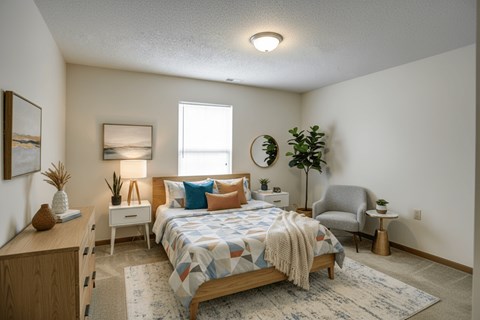 A bedroom with a bed, nightstand, and chair.