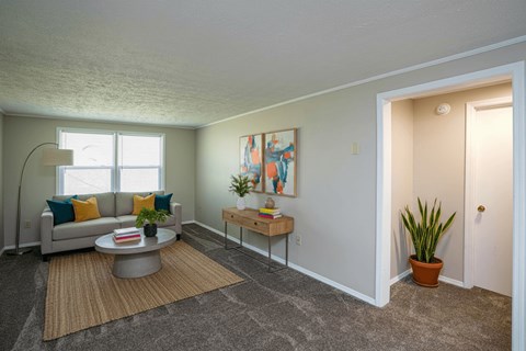 A living room with a grey couch, a coffee table, a potted plant, and a painting on the wall.