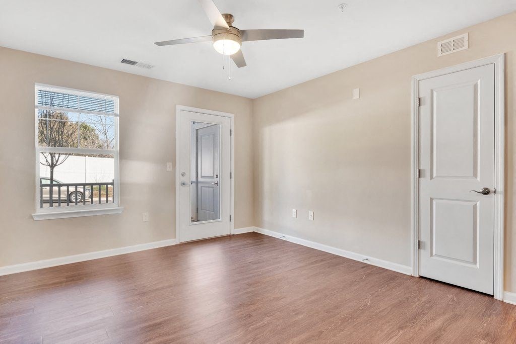 an empty living room with a ceiling fan and a window