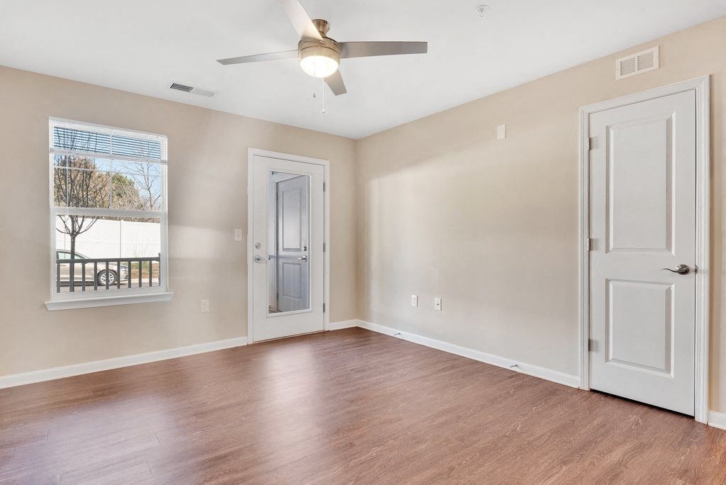 an empty living room with a ceiling fan and a window