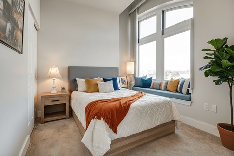 A bedroom with a large bed and a potted plant.