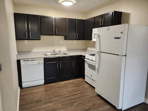 A kitchen with black cabinets and a white refrigerator.