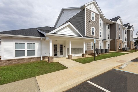 A large apartment complex with multiple buildings and a driveway in front.