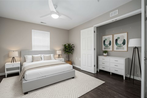 A bedroom with a large bed, a ceiling fan, and a plant.