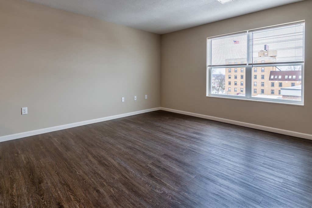 an empty living room with wood floors and a large window