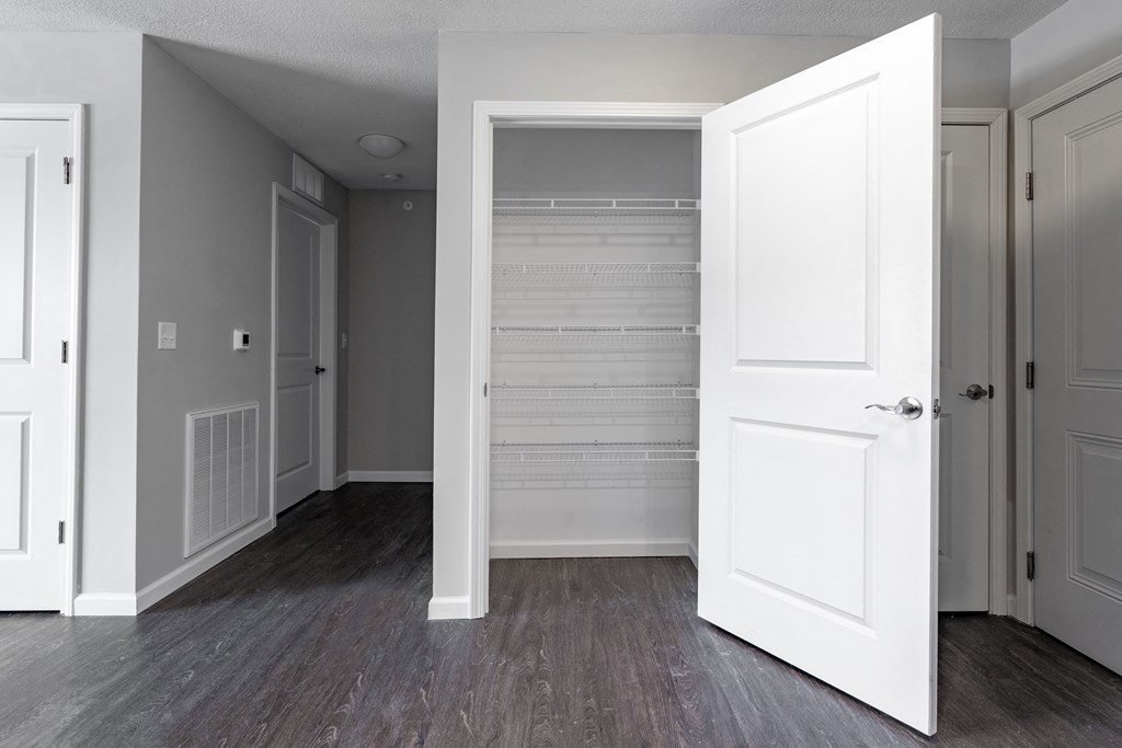 an empty room with a white door open to a walk in closet