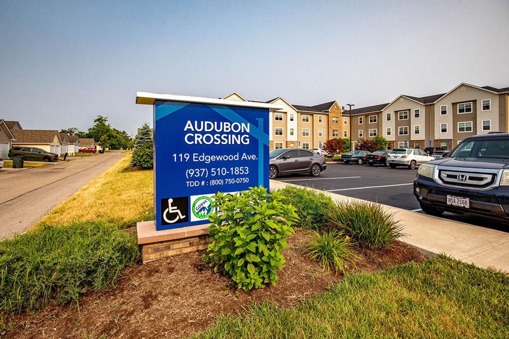 a sign in a parking lot with a building in the background