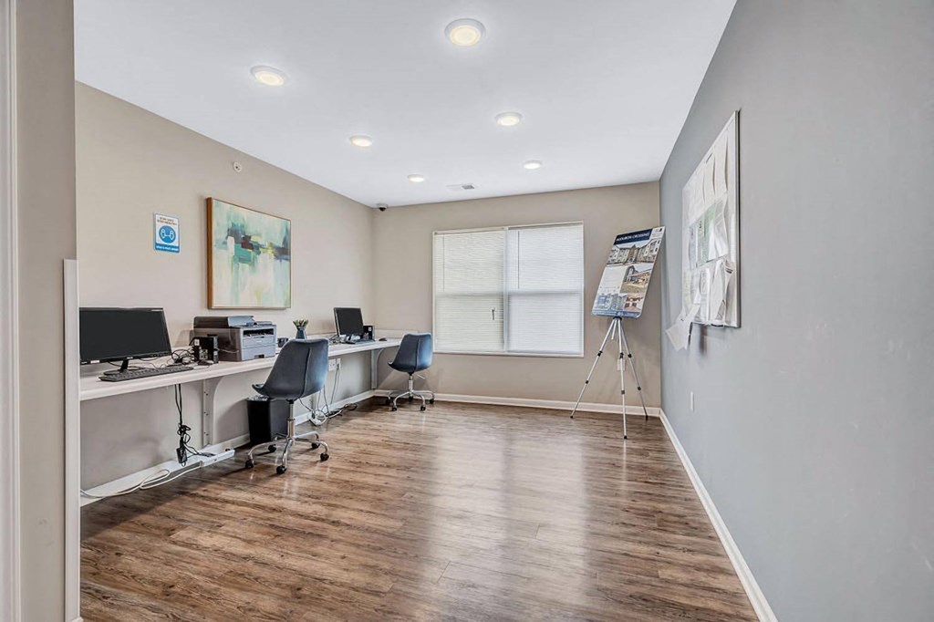 a room with two desks with computers on them and a window in the background