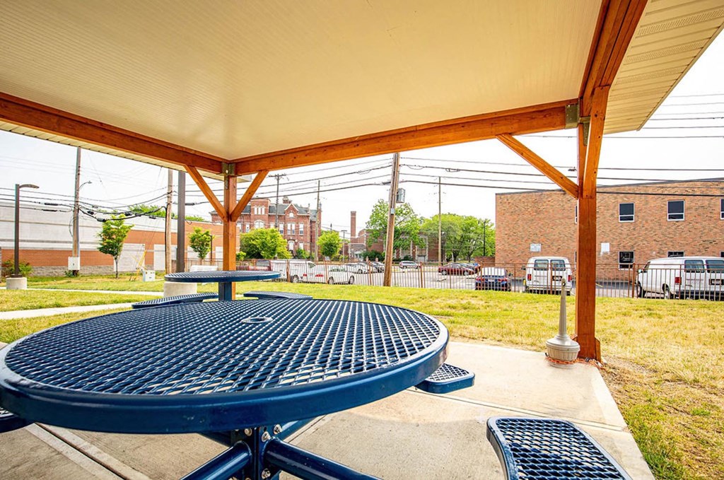 a picnic area with a table and benches and a building in the background