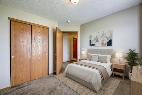 A bedroom with a large bed and a plant on the nightstand.