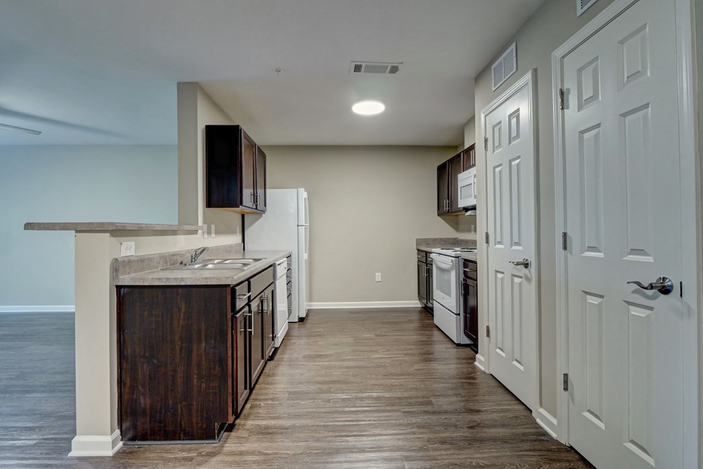 an empty kitchen with white appliances and a wood floor