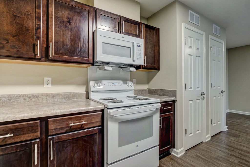 an empty kitchen with white appliances and wooden cabinets