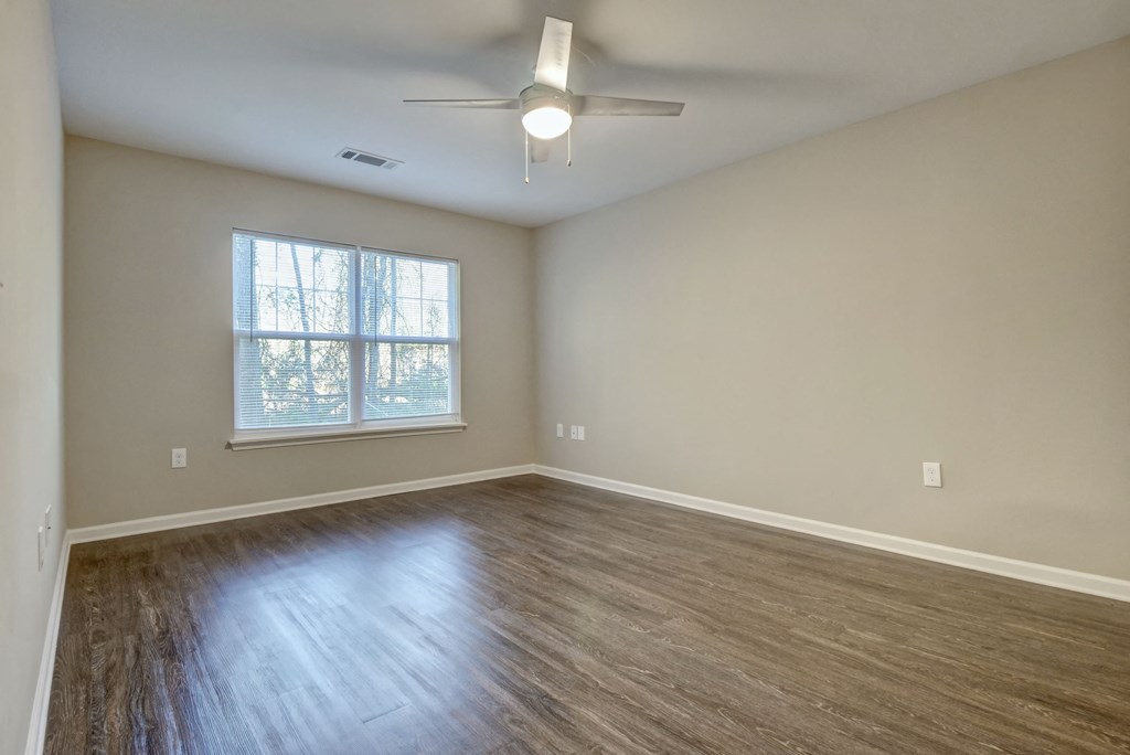 an empty living room with wood floors and a ceiling fan