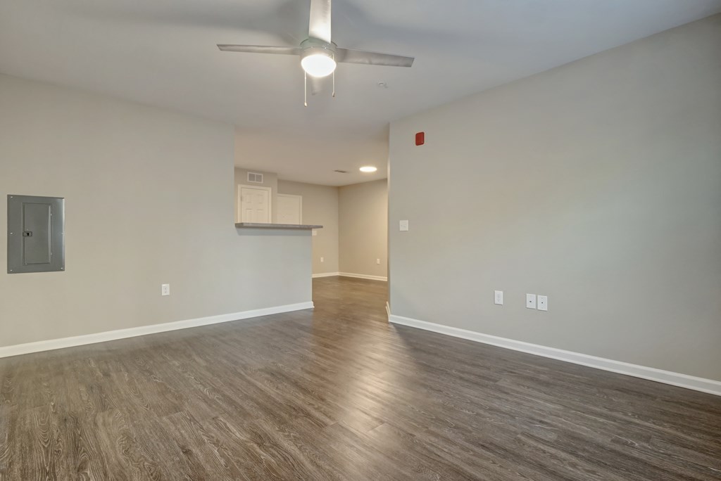 an empty living room with wood floors and a ceiling fan
