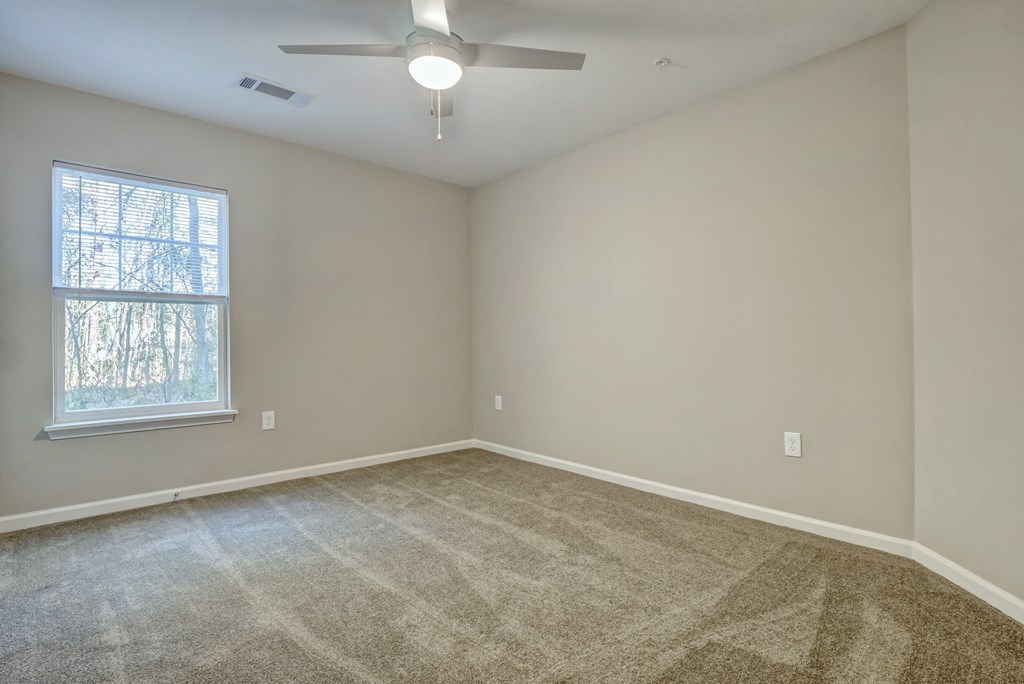an empty living room with carpet and a ceiling fan