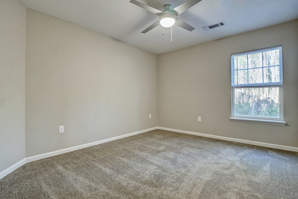 an empty living room with carpet and a ceiling fan