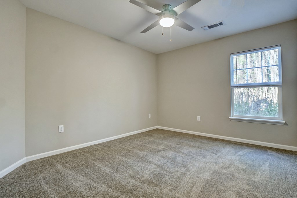 an empty living room with carpet and a ceiling fan