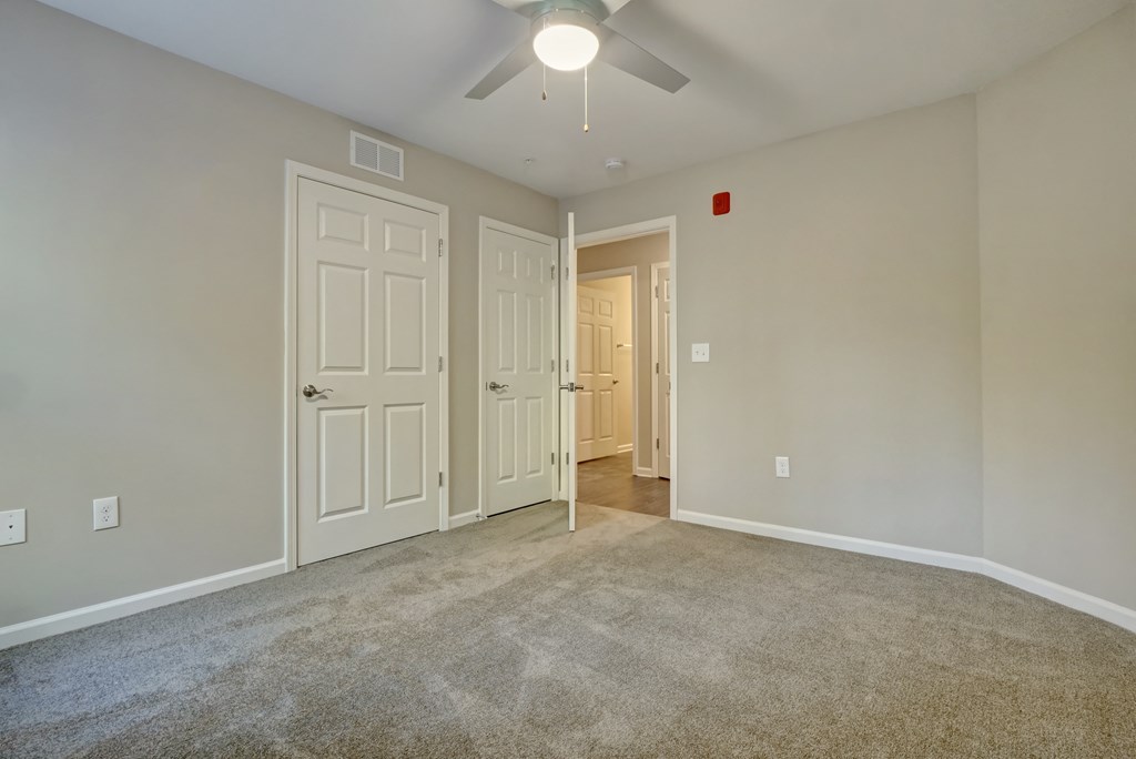 an empty living room with two doors and a ceiling fan
