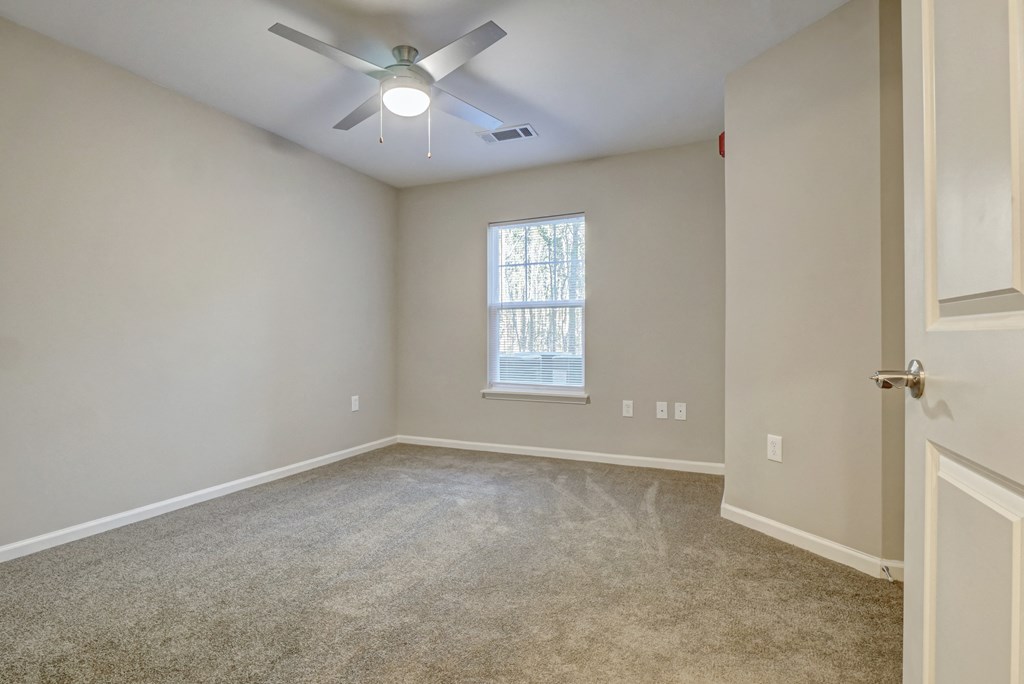 an empty room with a ceiling fan and a window