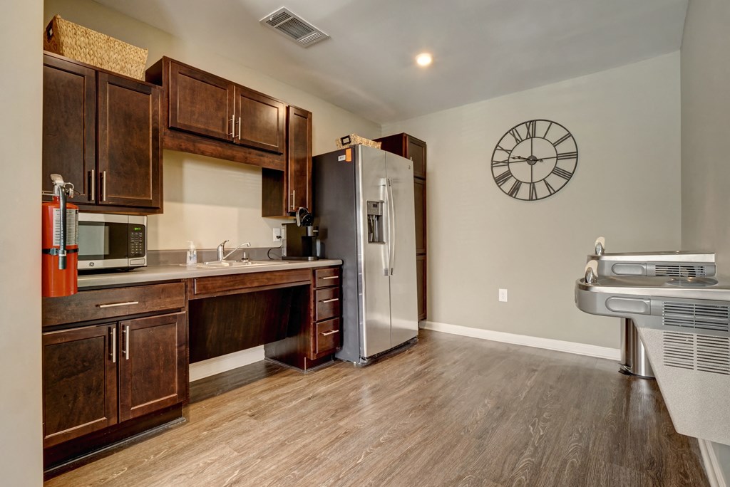 full kitchen with stainless steel appliances and wooden cabinets and a wall clock