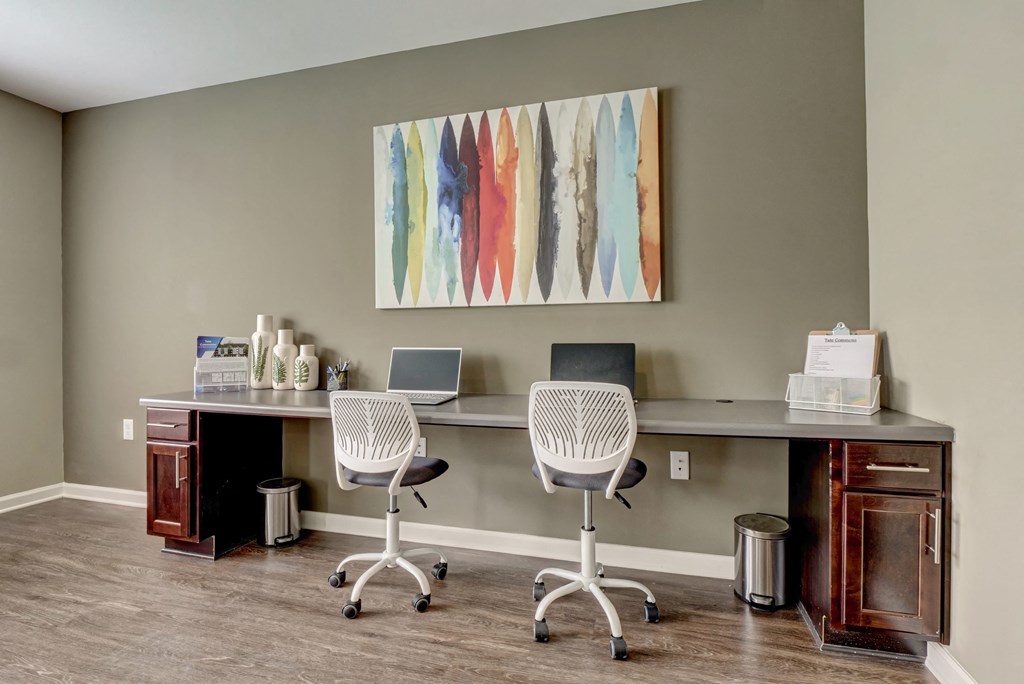 a home office with two desks and two chairs and a laptop