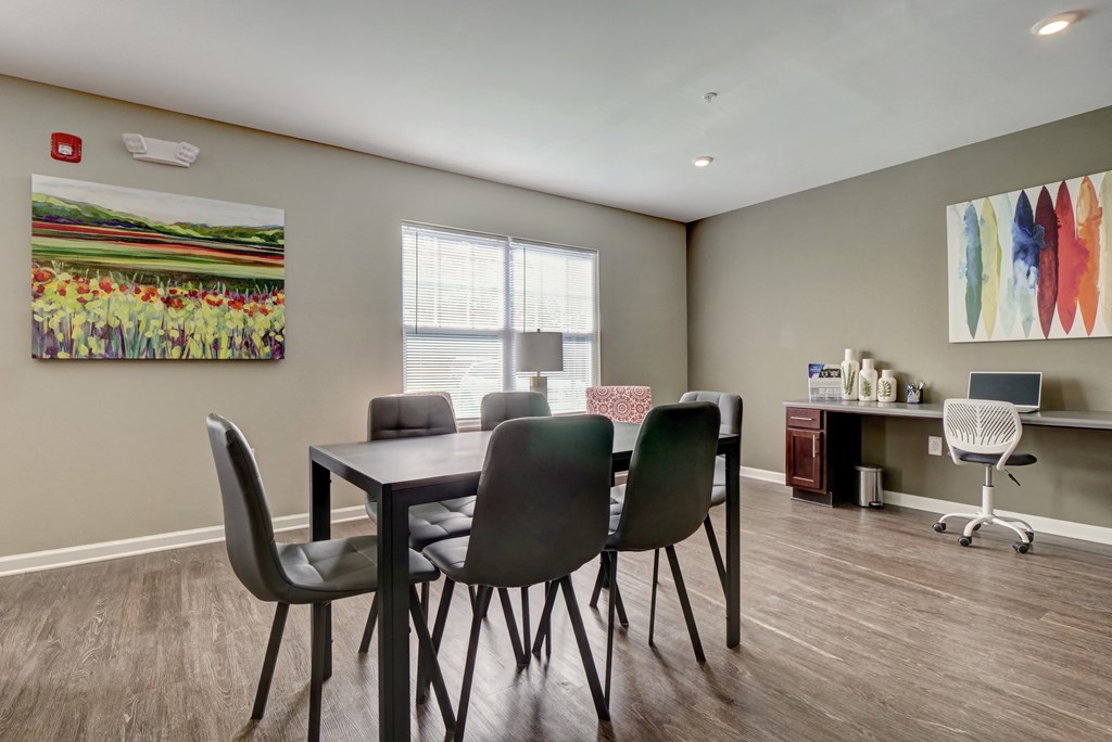 a dining room with a table and chairs and a desk with a computer