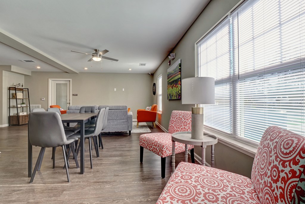 a living room with a dining room table and chairs and large windows