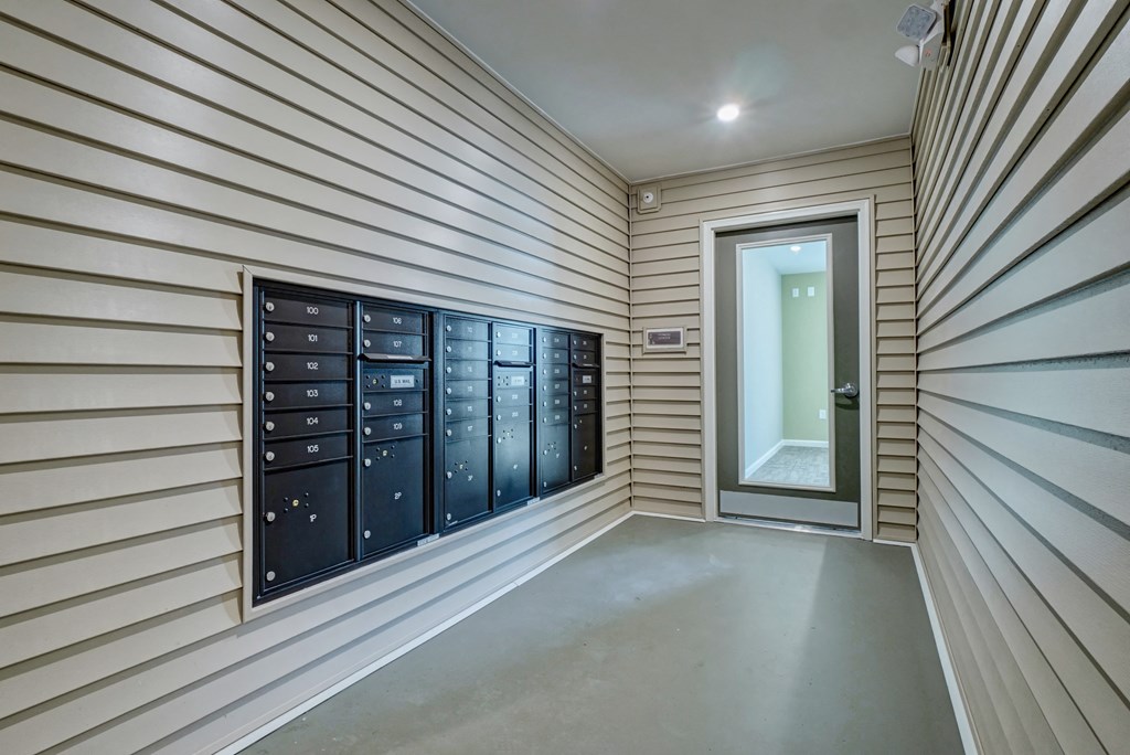 a hallway with a row of mailboxes and a door to a mail room