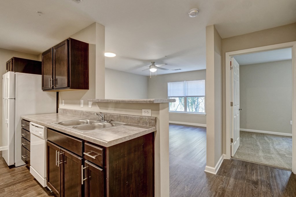 an empty kitchen with an open door to a living room