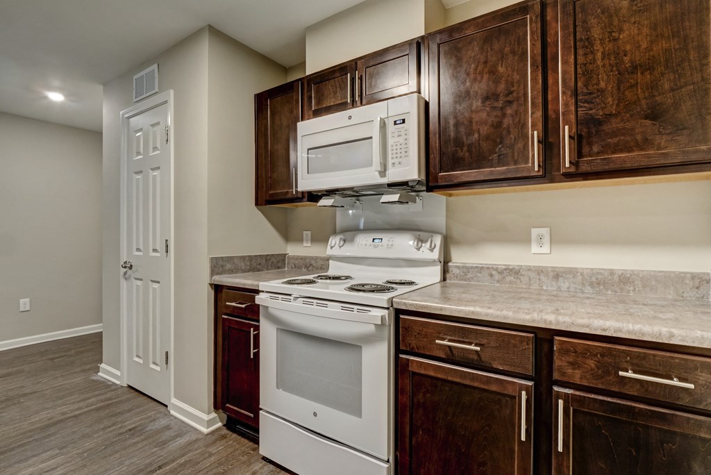 an empty kitchen with white appliances and wooden cabinets