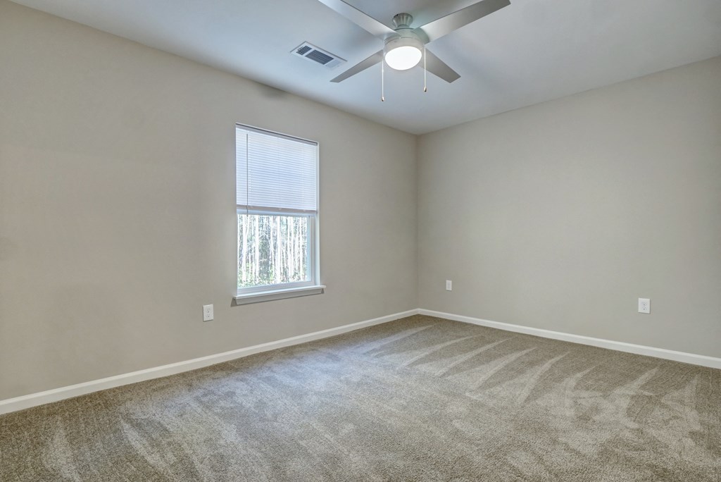 an empty room with a ceiling fan and a window