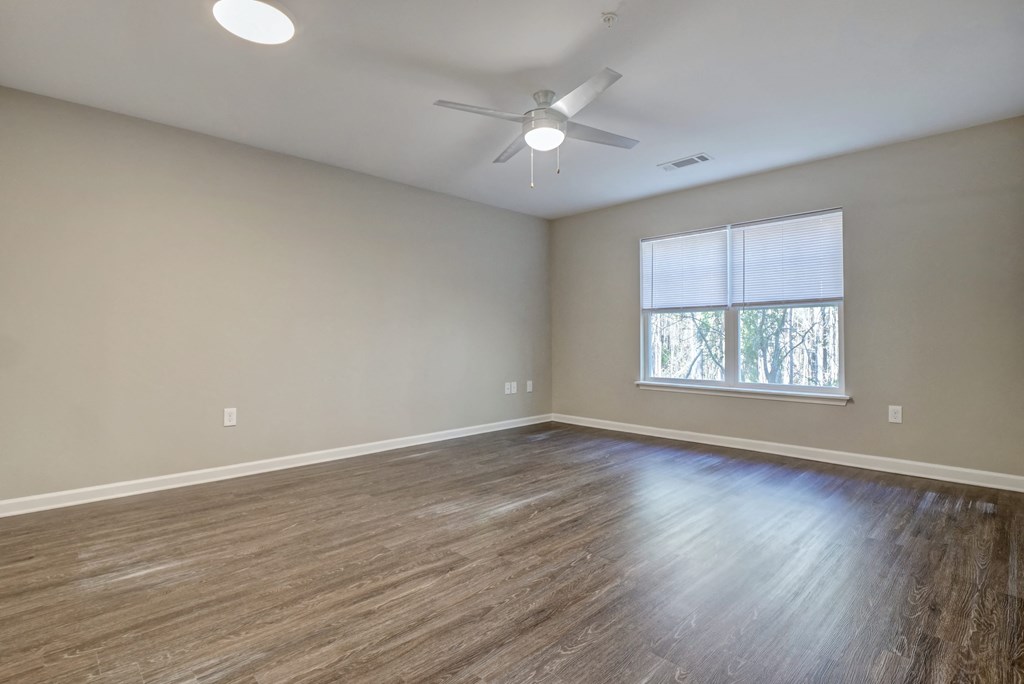 an empty living room with a ceiling fan and a window