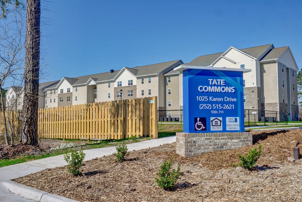 a sign in front of an apartment building with apartments in the background