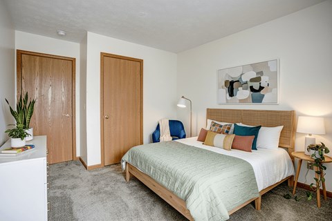 A bedroom with a bed, nightstand, and two doors.