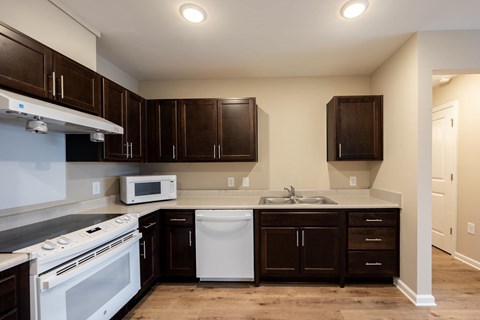 A kitchen with brown cabinets and a white dishwasher.