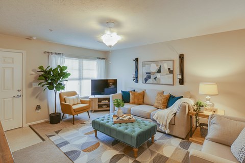 A living room with a blue ottoman and a white couch.