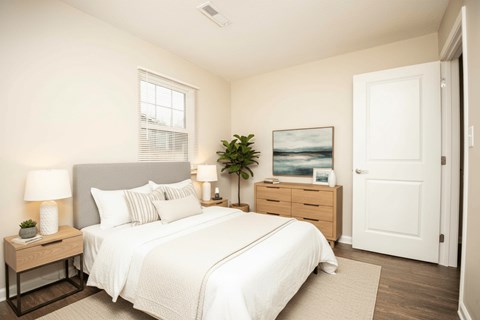 A bedroom with a large bed, a nightstand with a lamp, and a painting on the wall.