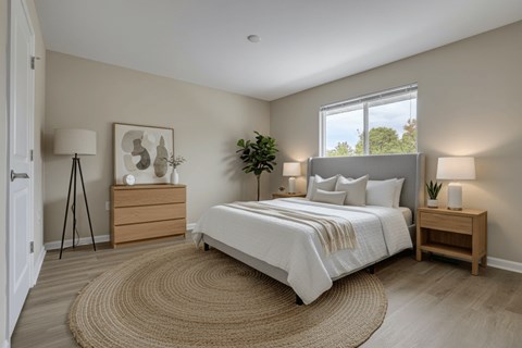 A bedroom with a large bed, a nightstand, and a rug on the floor.