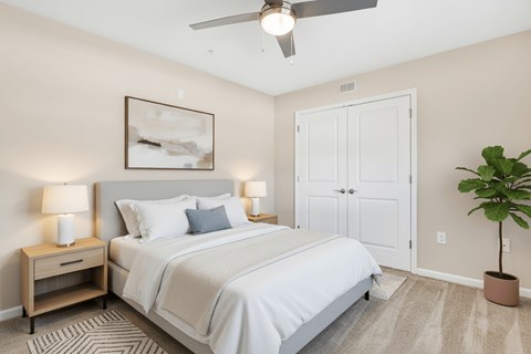A bedroom with a bed, nightstands, and a plant.
