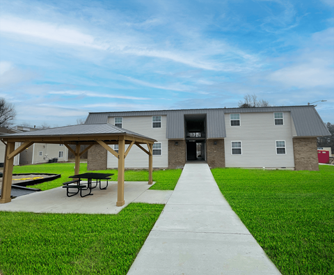 the back of a building with a picnic area and a sidewalk